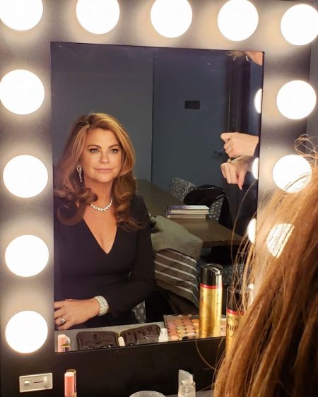 Kathy Ireland in front of a mirror doing her make-up.